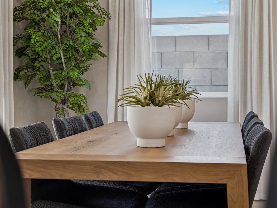 A table with a potted plant on it and a window with a brick wall and a brick.