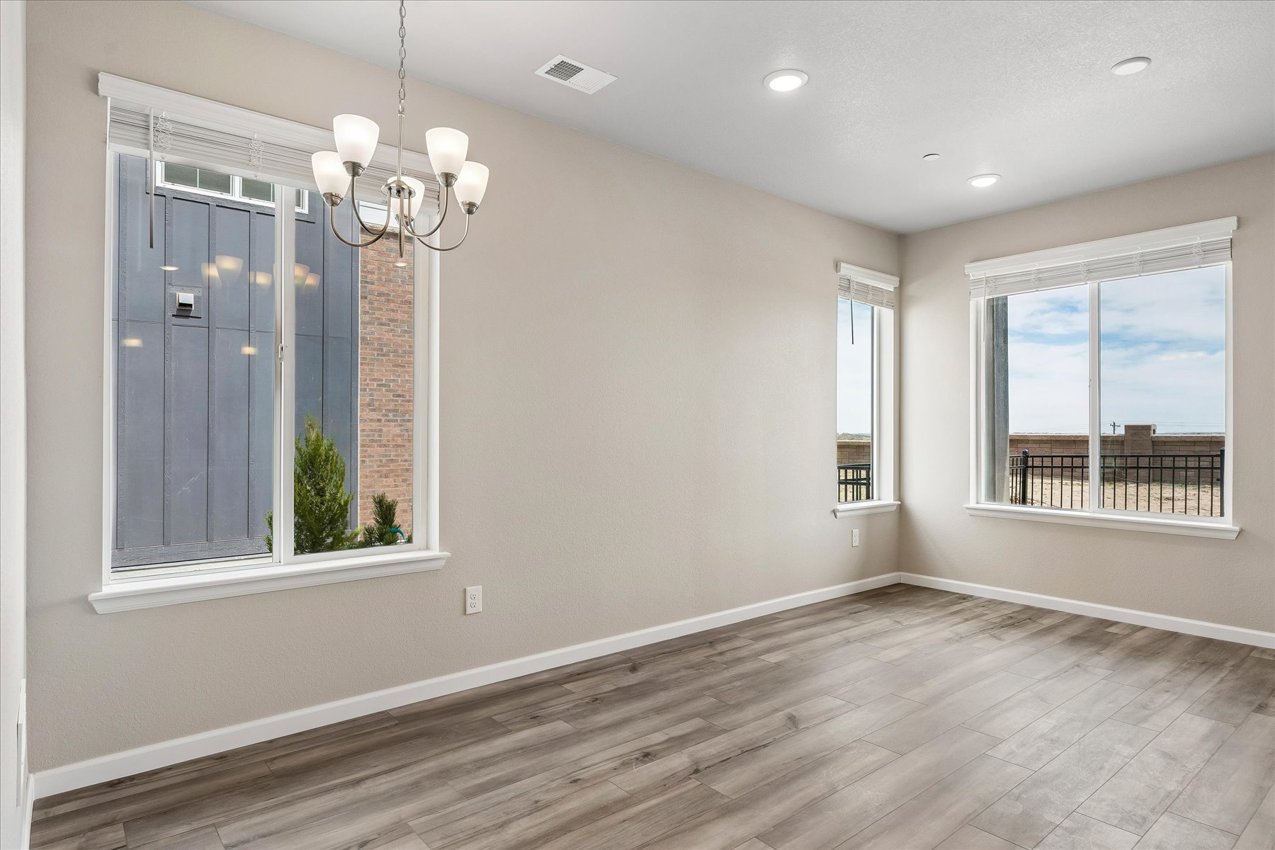 A room with a wood floor and a wood floor with a chandelier and a window with.