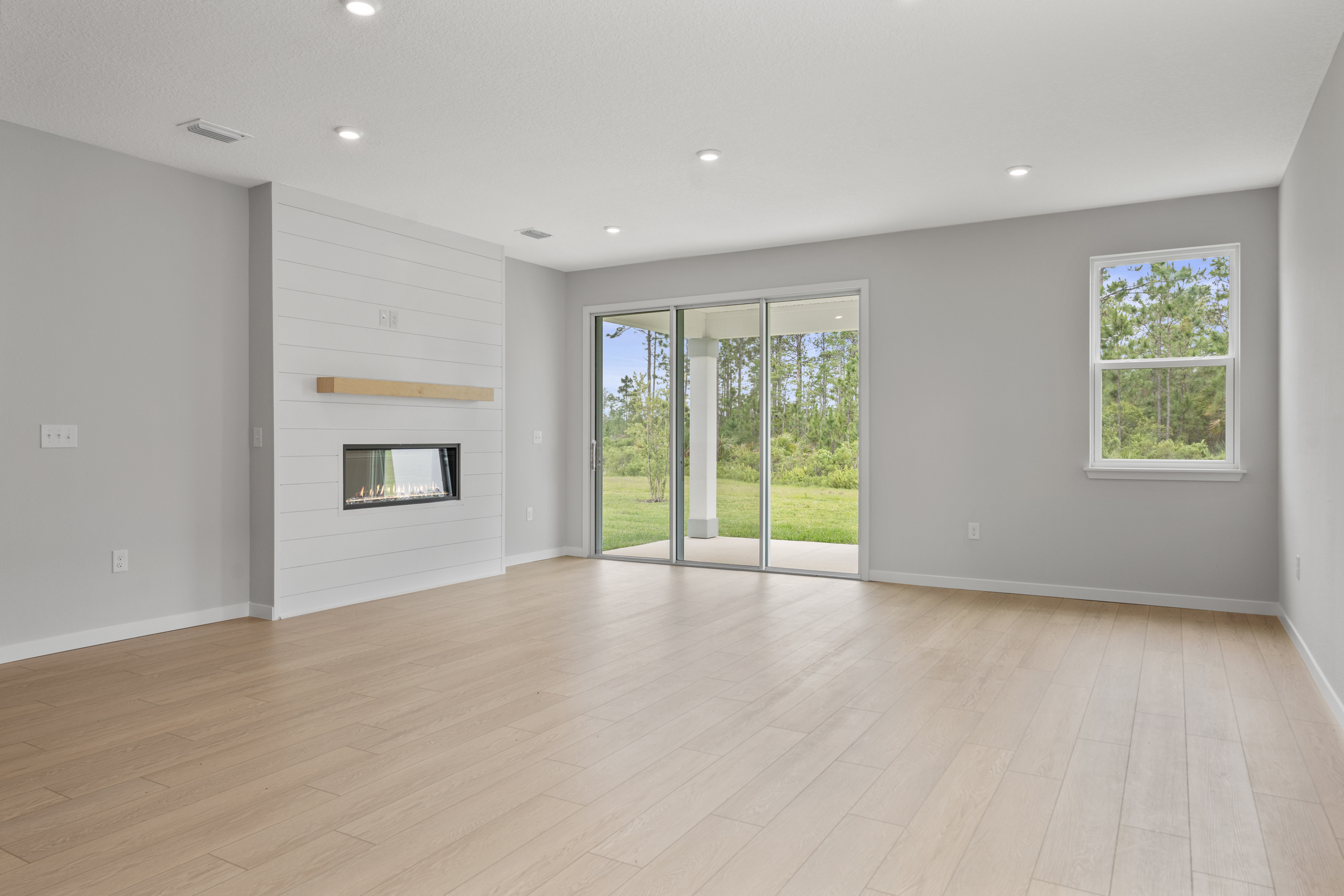 Charleston II Floorplan Lot 144 Great Room with Fireplace and Triple Slider Patio Doors at Seminole Palms in Palm Coast