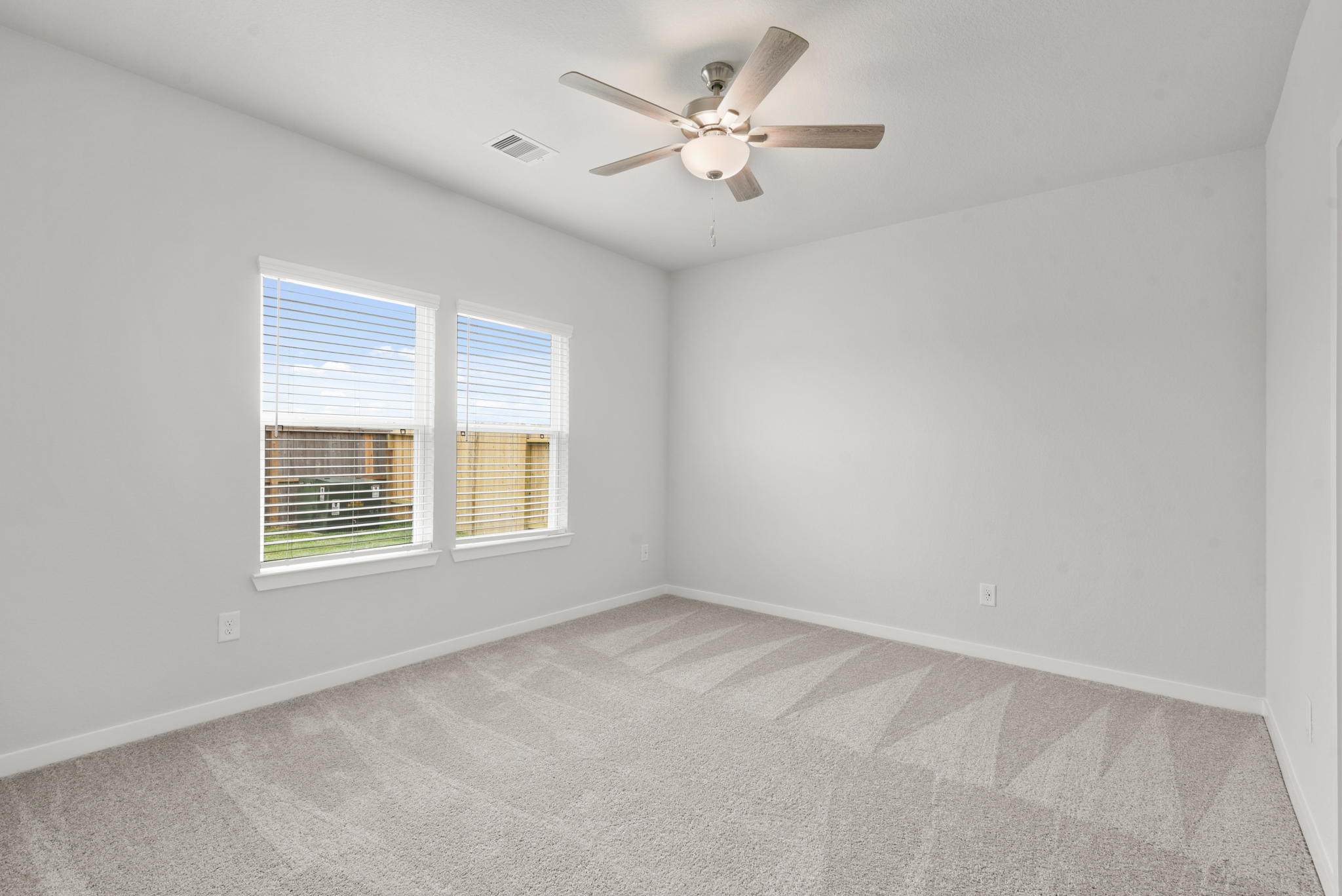 A room with a ceiling fan and a carpet.