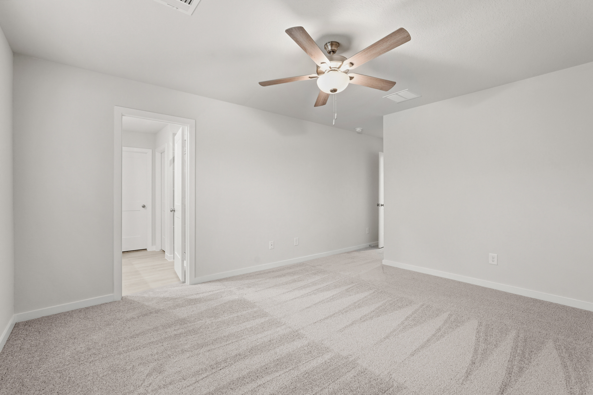 A room with a ceiling fan and white walls.