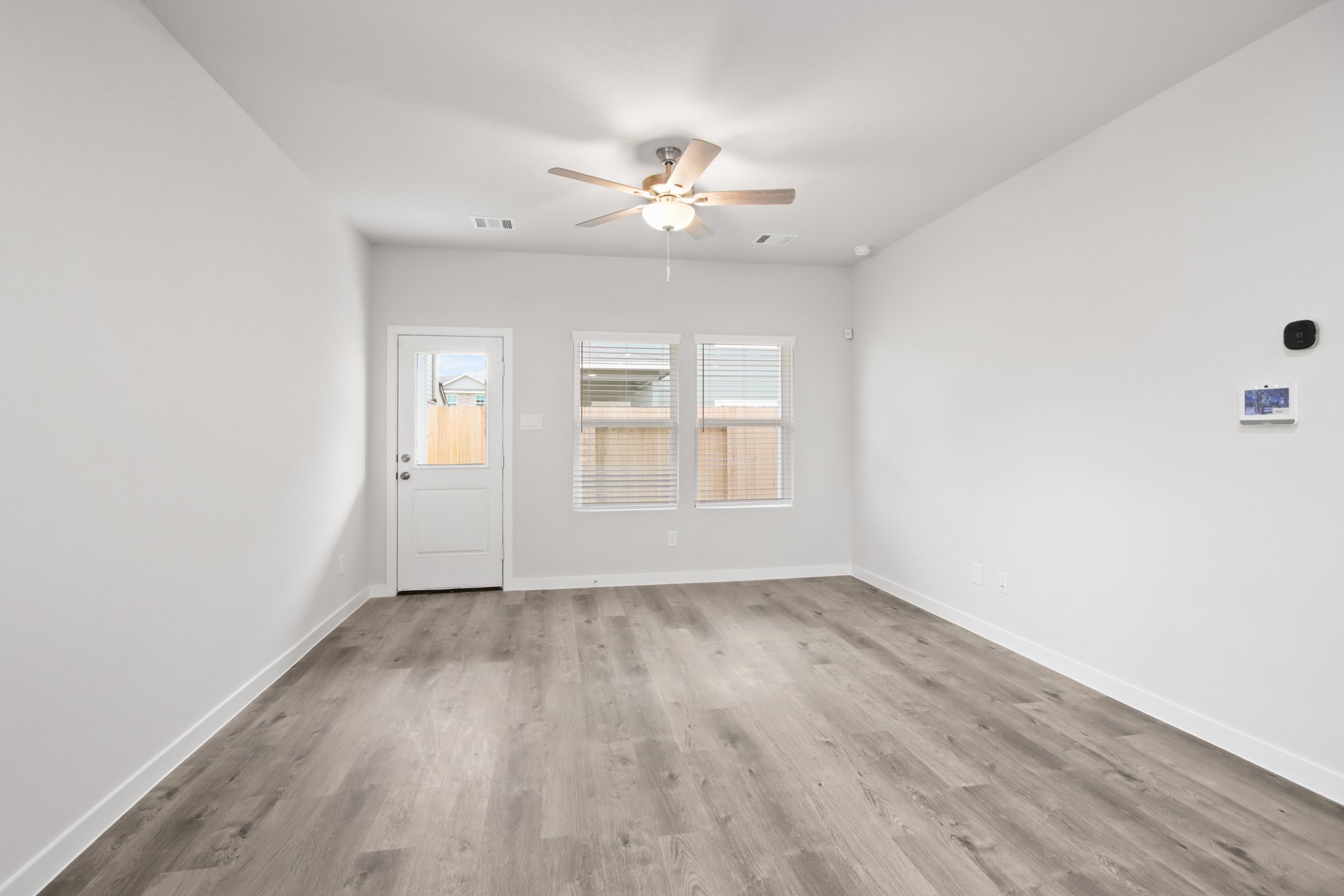 A room with a ceiling fan and a wood floor.