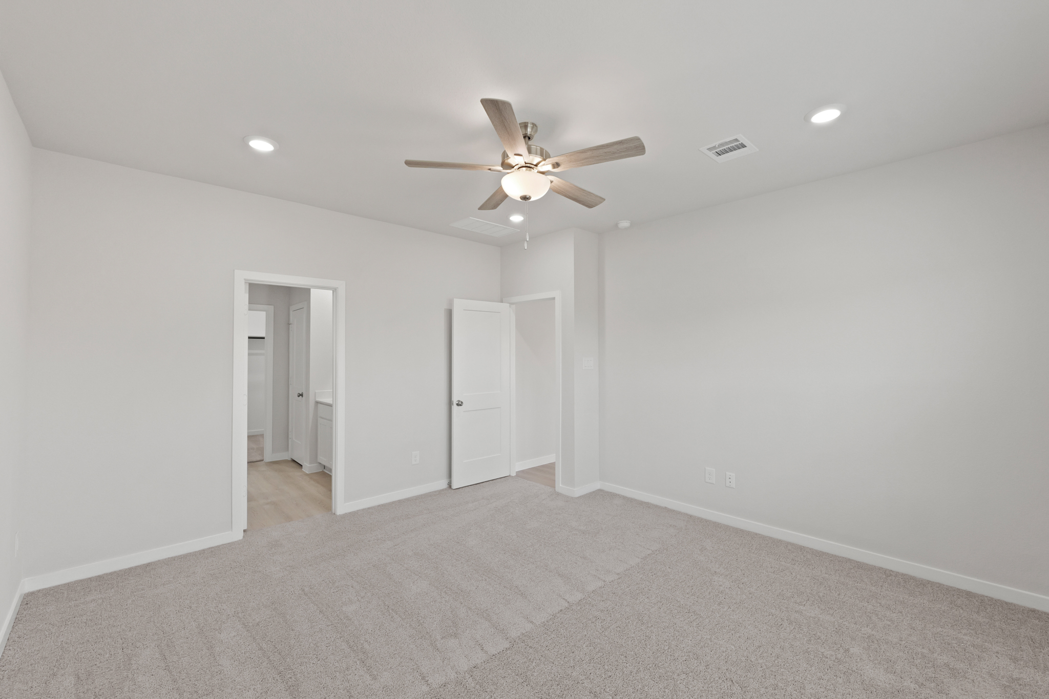A room with a ceiling fan and a carpet.