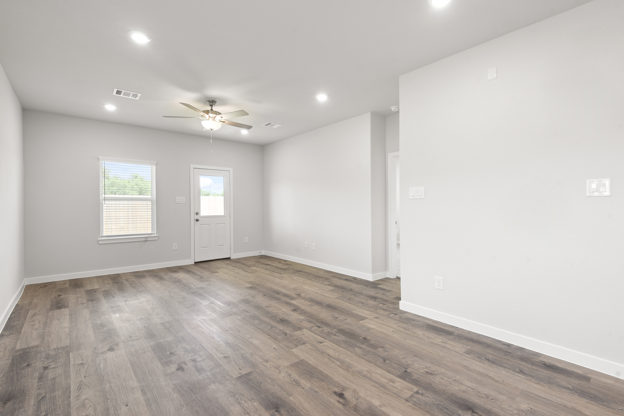 A room with a wood floor and a ceiling fan.