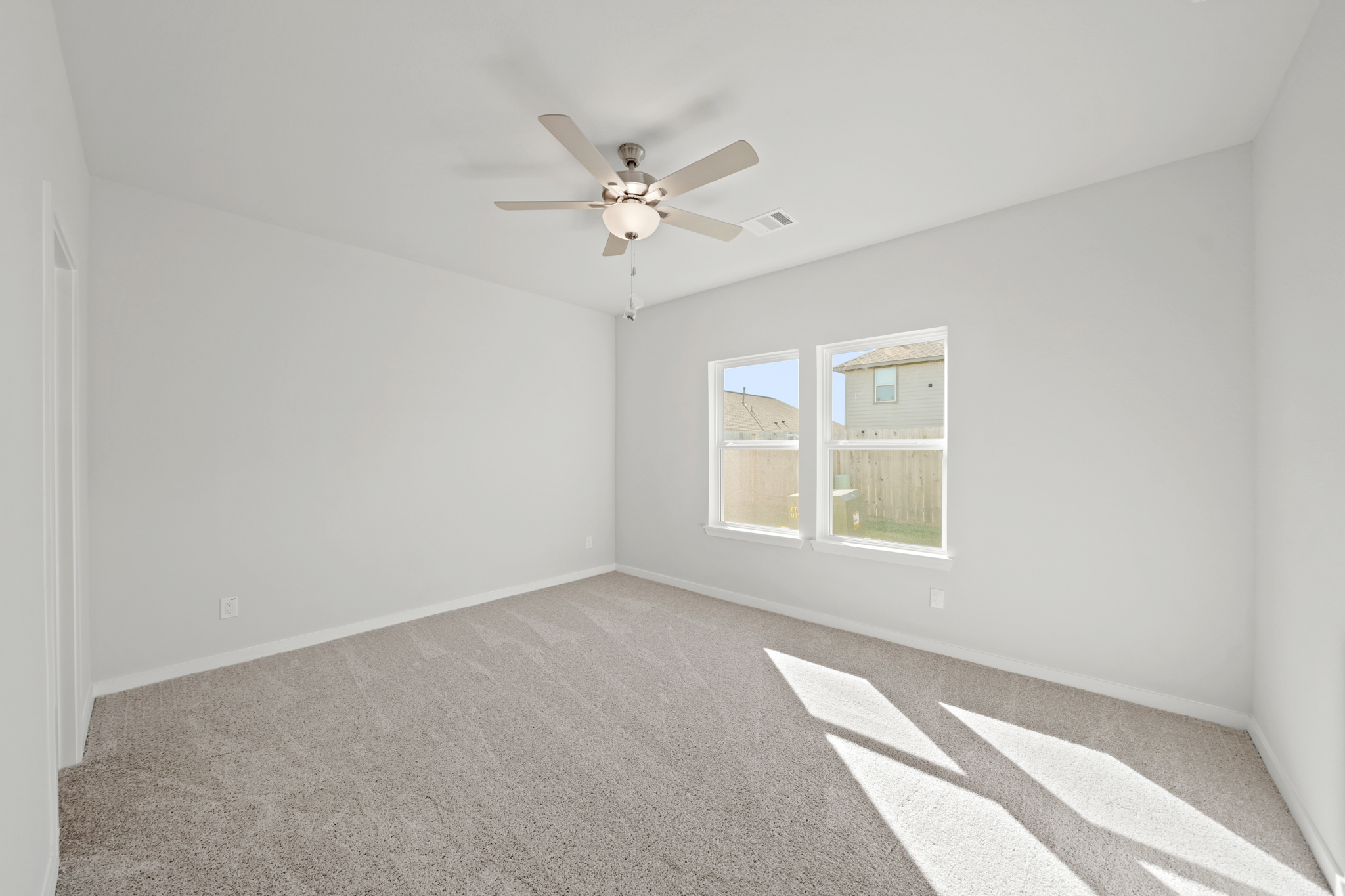A room with a ceiling fan and a carpet.