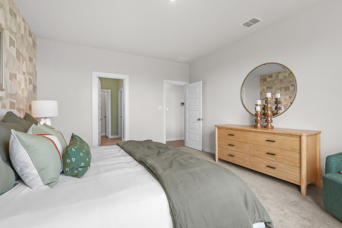 A bedroom with a bed and a mirror.