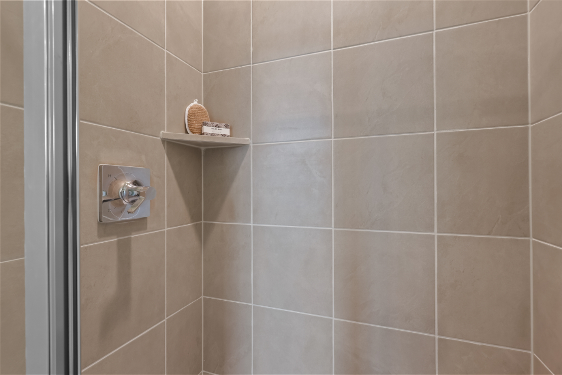 A shower with a shelf and a basket on it.
