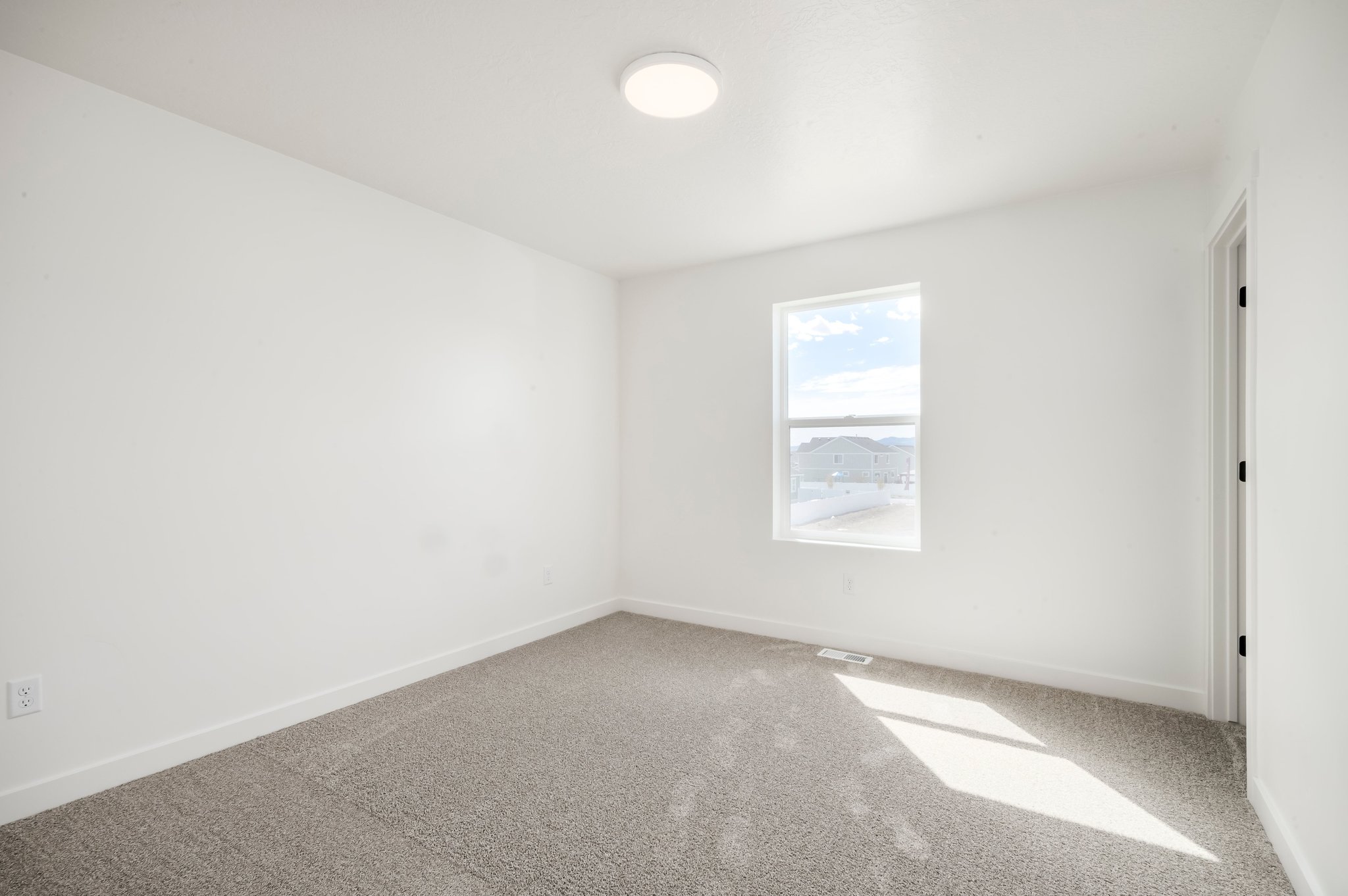 A room with a window and a rug.