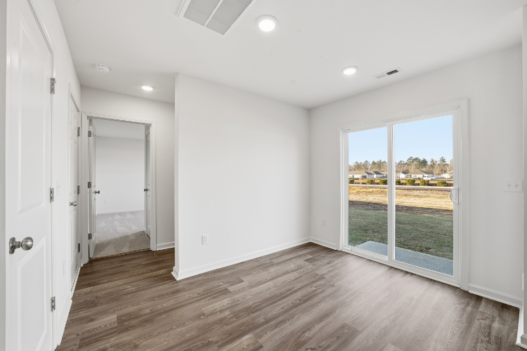 A room with a wood floor and a window with a view of a city.