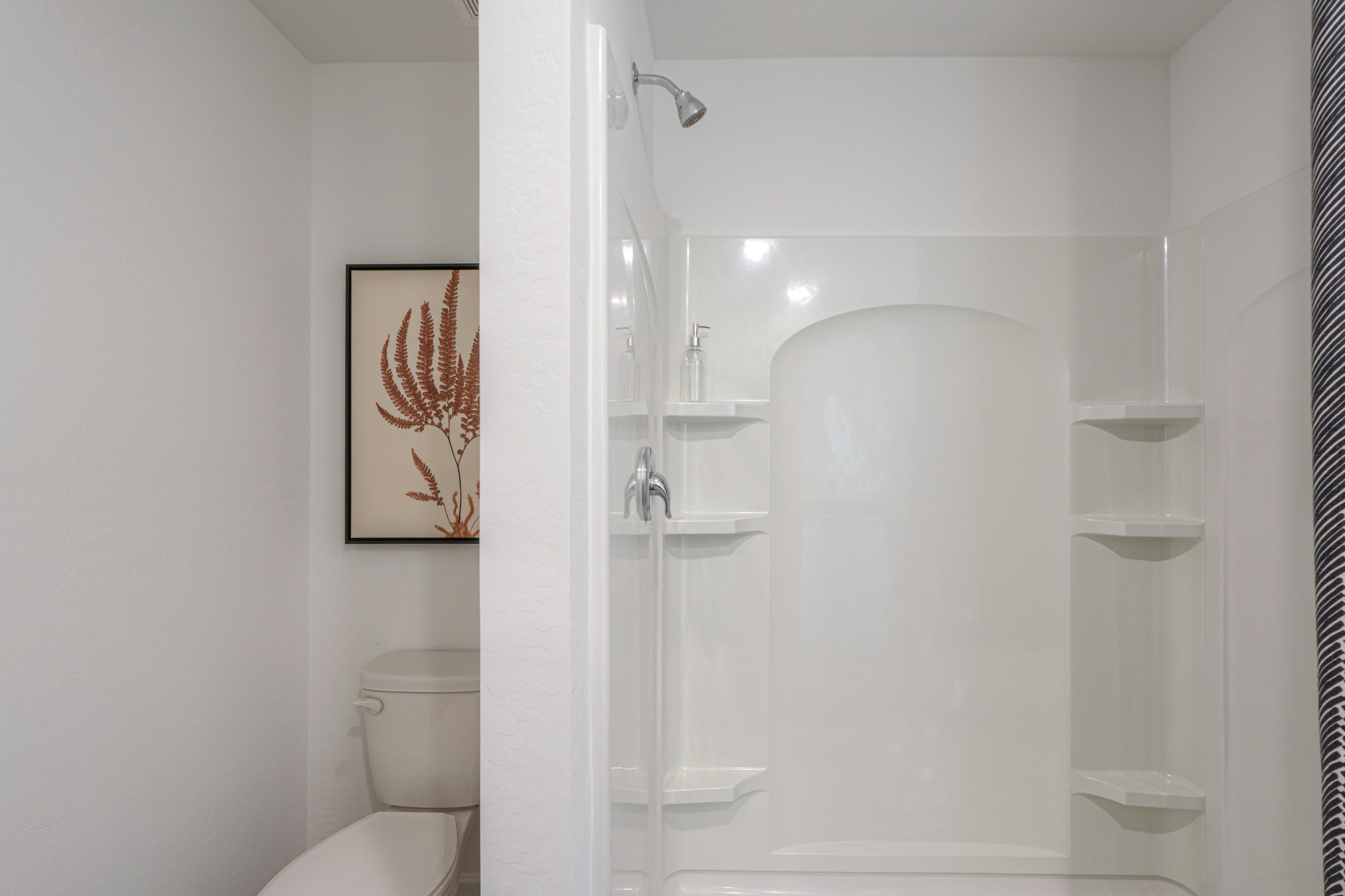 A bathroom with a shower unit and toilet.